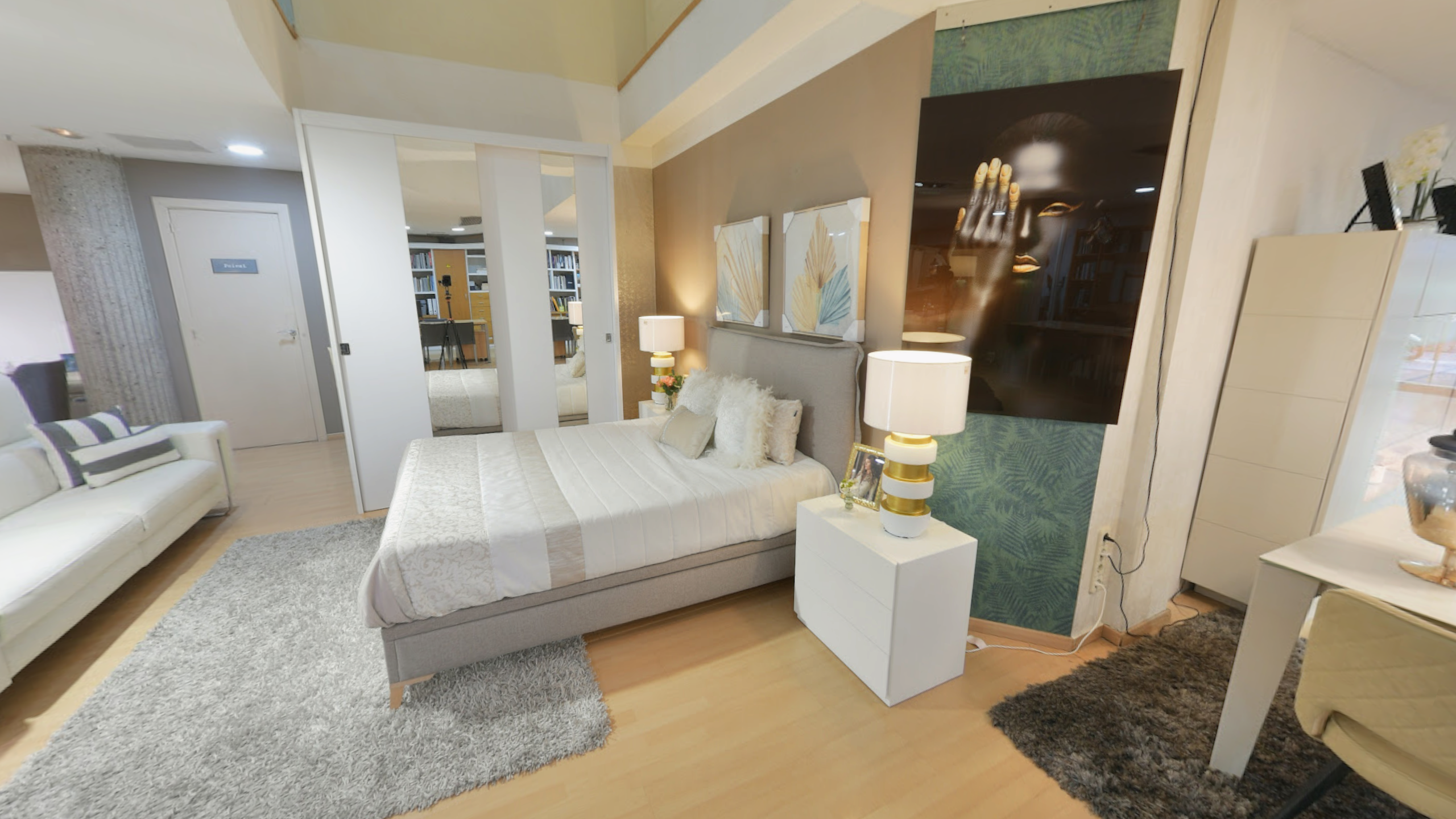 Tienda de Muebles en Barcelona, mobiliario a medida y diseño - Temas Mobiliario Dormitorio de matrimonio moderno en exposición con cama tapizada en gris, cabecero con cuadros decorativos y mesita de noche blanca con lámpara de diseño