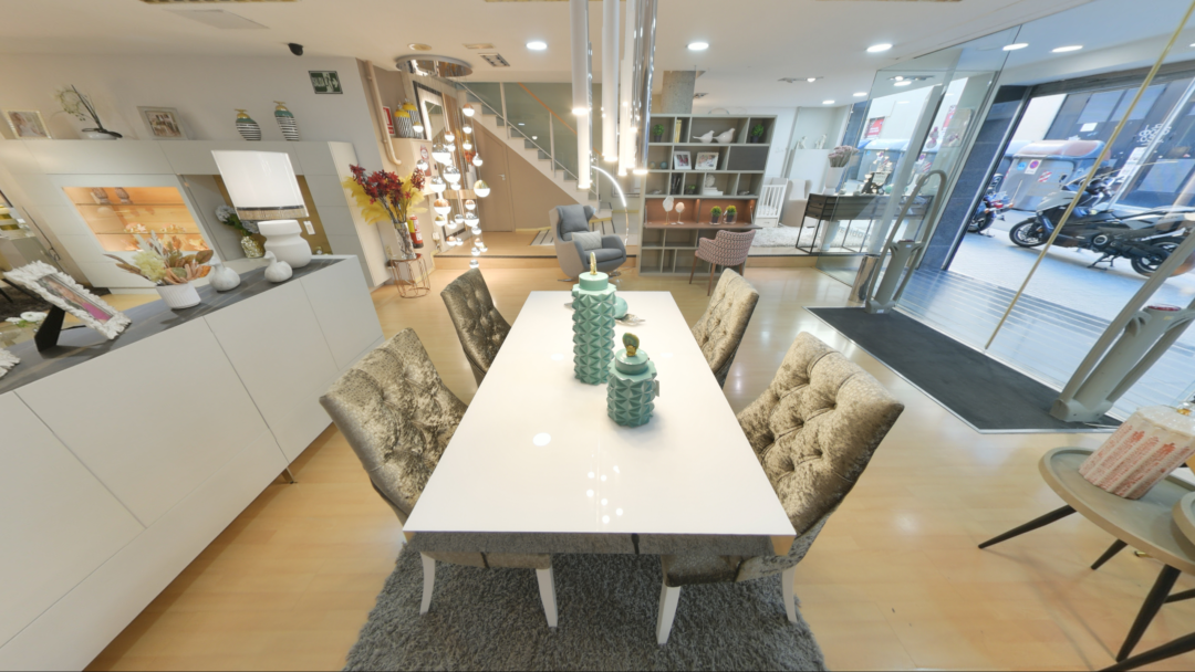 Tienda de Muebles en Barcelona, mobiliario a medida y diseño - Temas Mobiliario Vista de una amplia exposición de muebles que incluye una mesa de comedor blanca, un aparador moderno a la derecha y un sofá al fondo, con iluminación de diseño